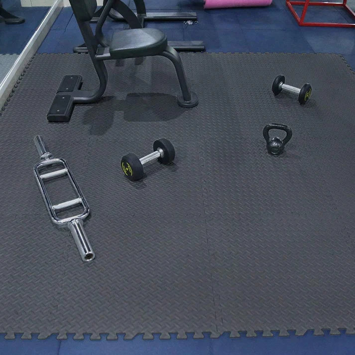 Gym equipment on a black interlocking mat in a gym setting