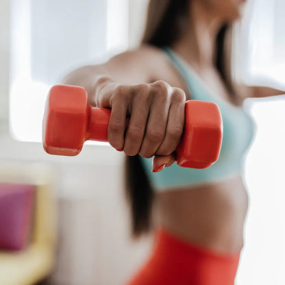 Person holding a red dumbbell with a blurred background